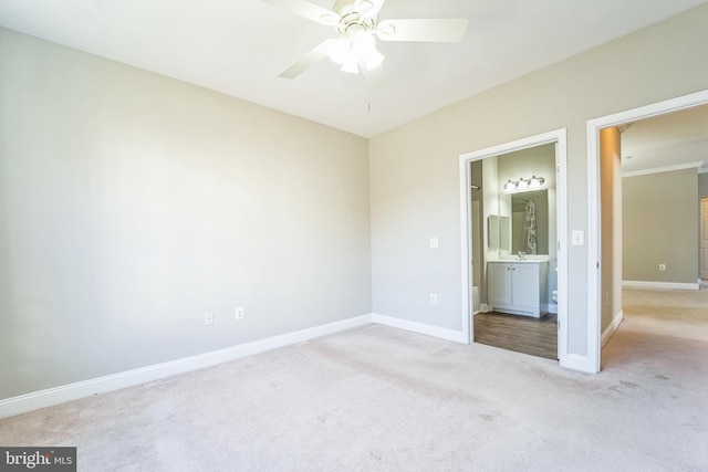 unfurnished bedroom with ceiling fan, light colored carpet, and ensuite bath