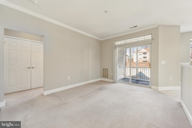 empty room with ornamental molding and light colored carpet