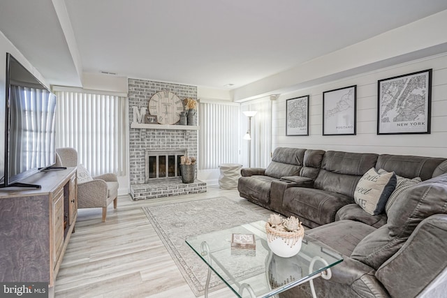 living room with a brick fireplace and light hardwood / wood-style floors