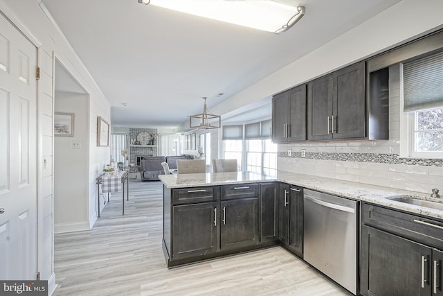 kitchen with backsplash, stainless steel dishwasher, kitchen peninsula, and a healthy amount of sunlight