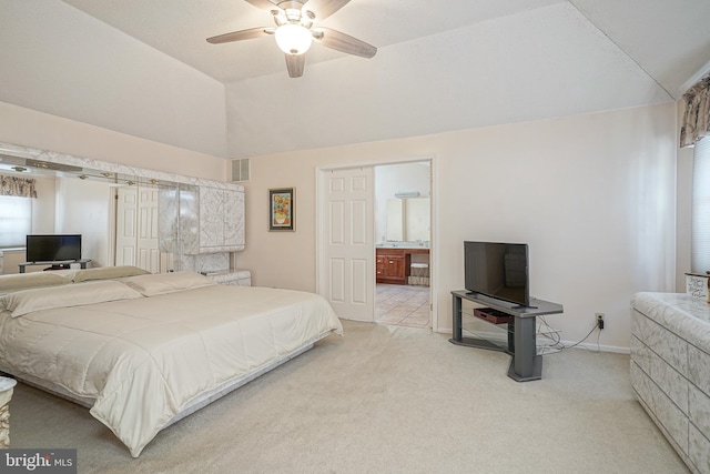 carpeted bedroom with vaulted ceiling, ceiling fan, and ensuite bath