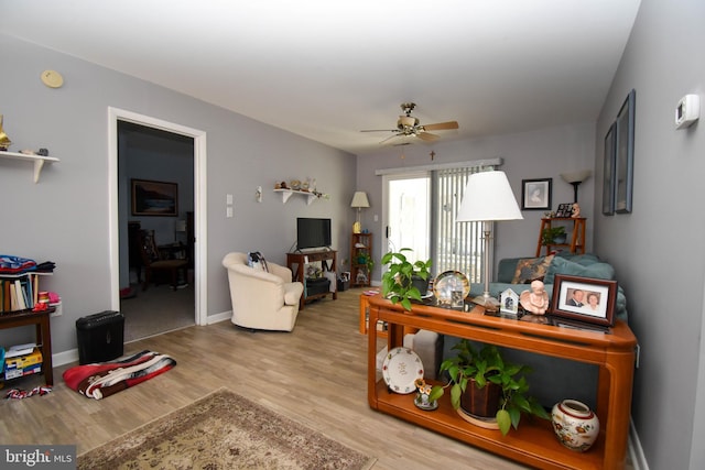 living room with light wood-type flooring, baseboards, and ceiling fan