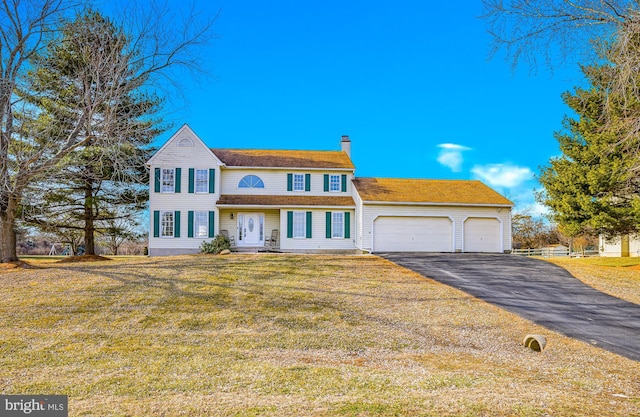 colonial home featuring a garage and a front lawn