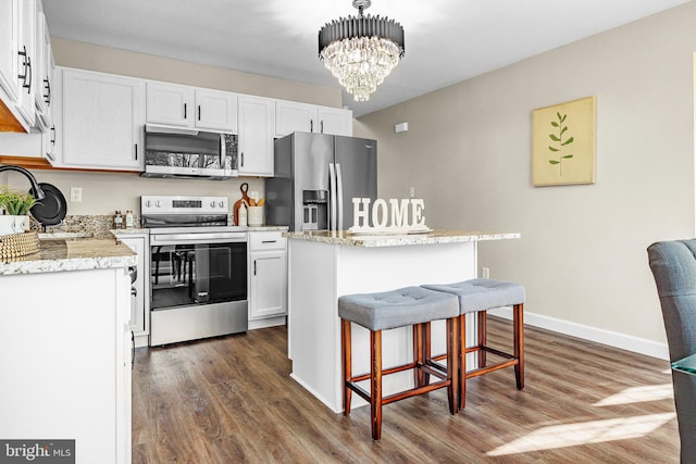 kitchen with white cabinetry, dark hardwood / wood-style floors, a kitchen island, pendant lighting, and stainless steel appliances