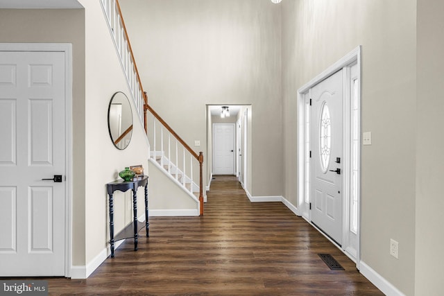 entrance foyer with dark hardwood / wood-style flooring and a towering ceiling