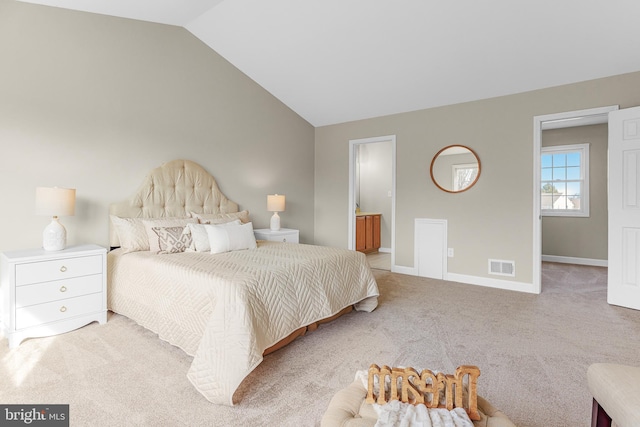 bedroom featuring vaulted ceiling, connected bathroom, and light carpet