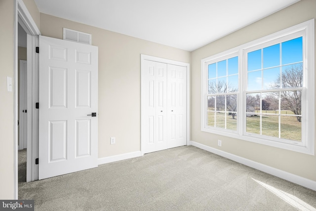 unfurnished bedroom featuring light carpet and a closet