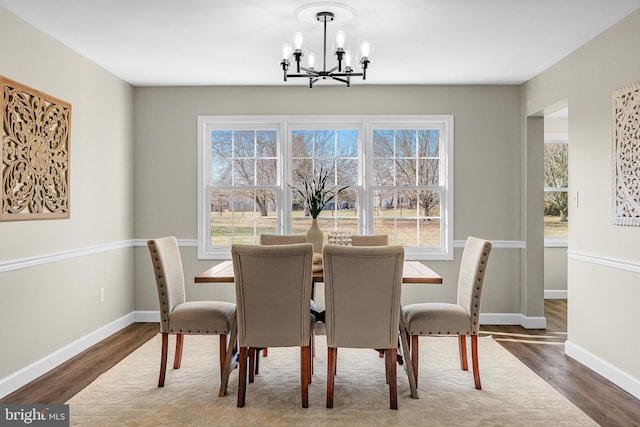 dining area with plenty of natural light, a notable chandelier, and dark hardwood / wood-style flooring