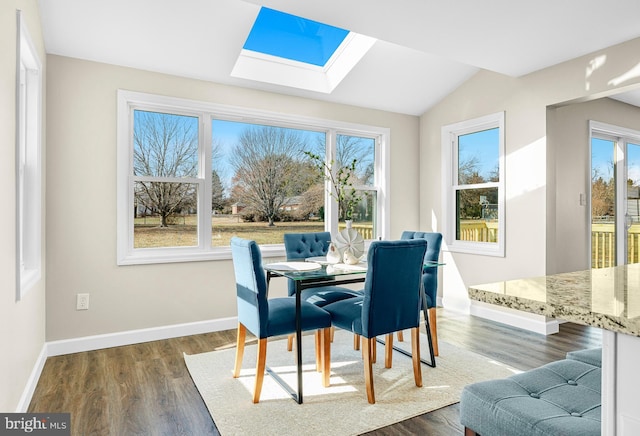 dining area with dark hardwood / wood-style floors and vaulted ceiling with skylight