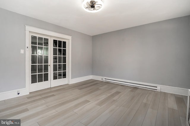 spare room featuring a baseboard radiator, light hardwood / wood-style floors, and french doors