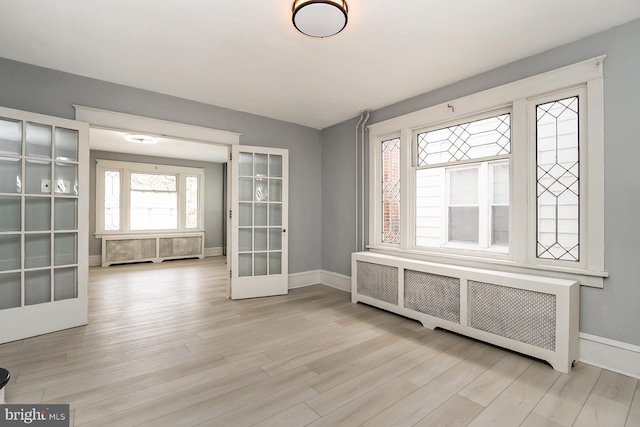 interior space with radiator heating unit, light wood-type flooring, and french doors