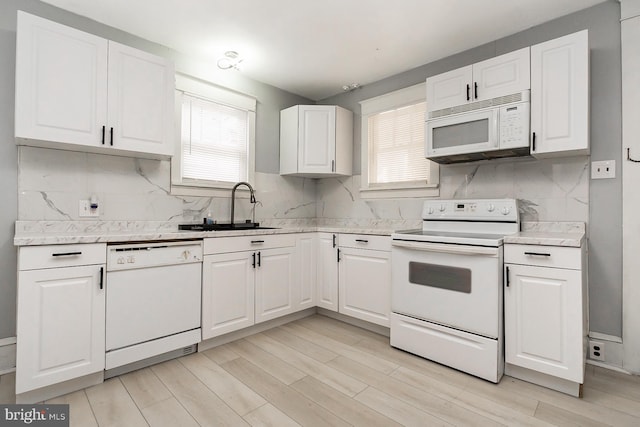 kitchen with white cabinetry, sink, backsplash, light hardwood / wood-style floors, and white appliances