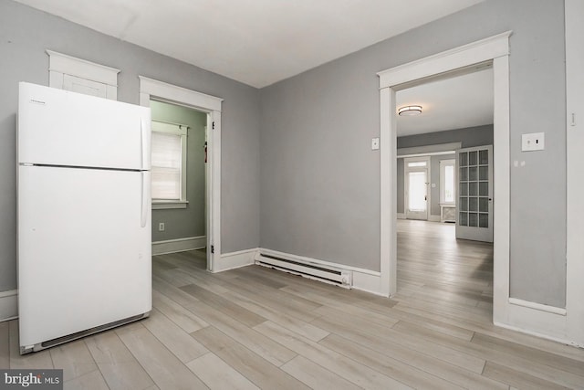 kitchen with light hardwood / wood-style flooring, a baseboard radiator, and white fridge