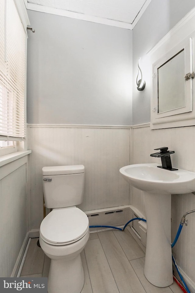 bathroom with crown molding, a healthy amount of sunlight, and toilet