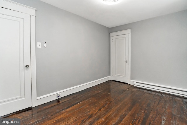 empty room with a baseboard heating unit and dark hardwood / wood-style flooring