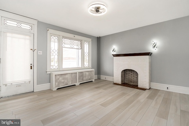 unfurnished living room featuring light hardwood / wood-style flooring, radiator, and a fireplace