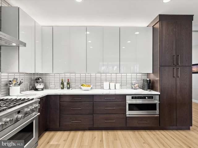 kitchen featuring white cabinetry, backsplash, stainless steel appliances, and light hardwood / wood-style floors