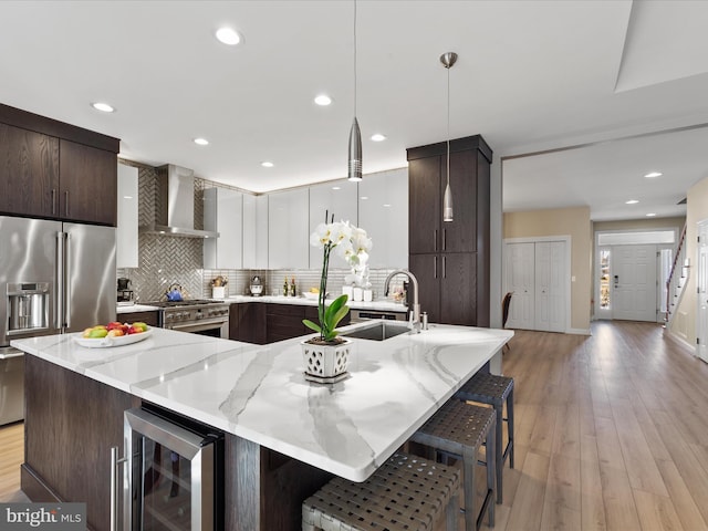 kitchen with a breakfast bar area, wall chimney range hood, wine cooler, and premium appliances