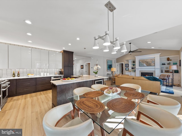 dining room featuring vaulted ceiling, sink, ceiling fan, and light hardwood / wood-style flooring