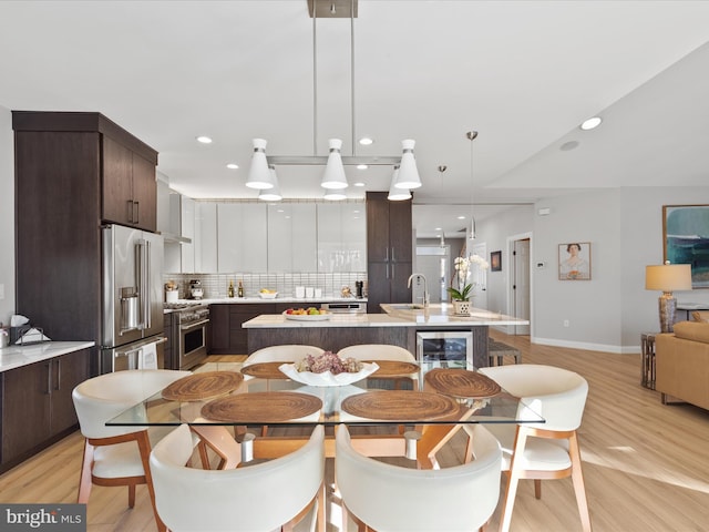 dining area featuring wine cooler, sink, and light wood-type flooring