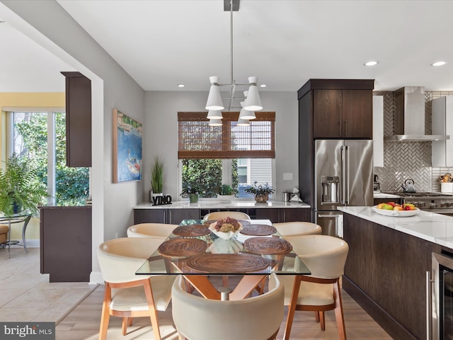 dining room featuring wine cooler, light hardwood / wood-style flooring, and a notable chandelier