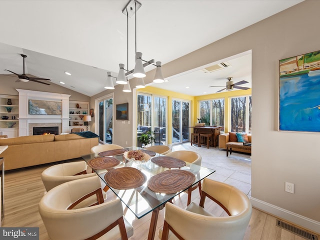 dining area featuring lofted ceiling, ceiling fan with notable chandelier, plenty of natural light, and built in features