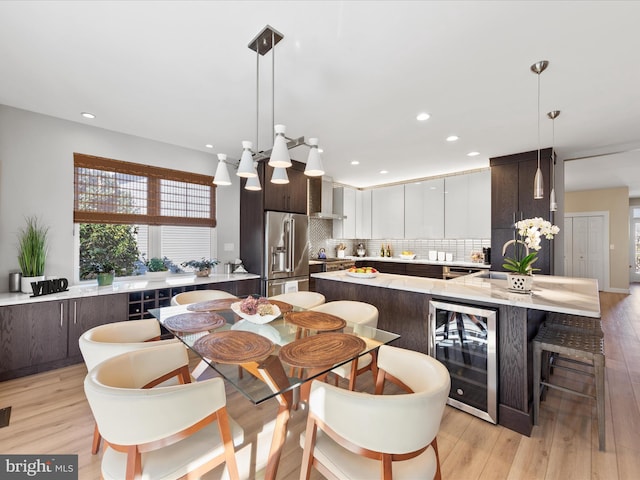 dining area with wine cooler and light hardwood / wood-style flooring