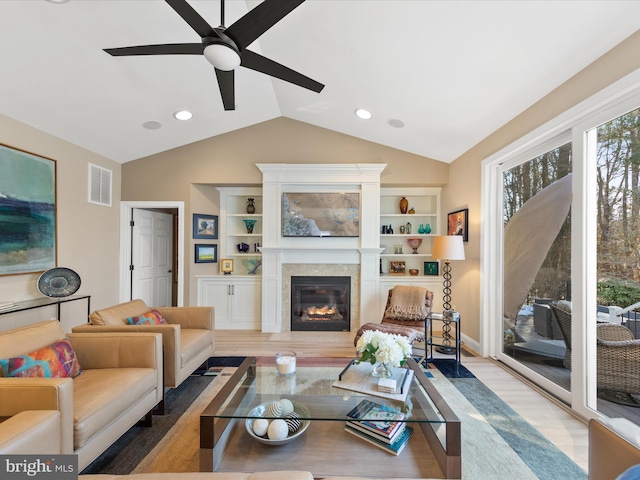 living room with lofted ceiling, hardwood / wood-style flooring, built in shelves, and ceiling fan