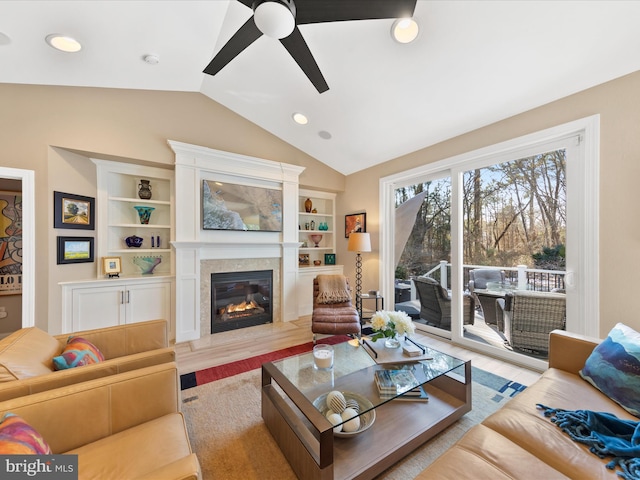 living room with lofted ceiling, a high end fireplace, light hardwood / wood-style floors, and built in shelves