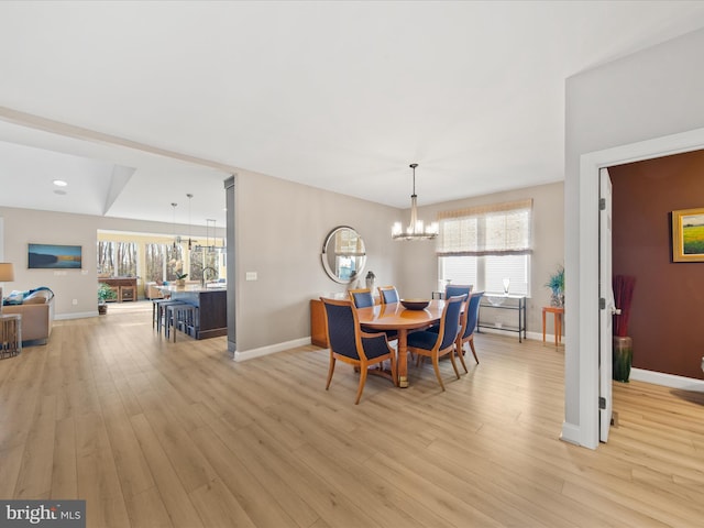 dining room with a notable chandelier, a wealth of natural light, and light wood-type flooring