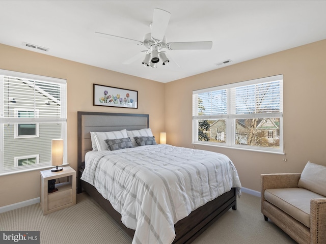 bedroom with ceiling fan, light colored carpet, and multiple windows