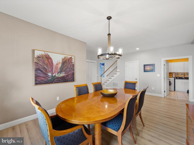 dining space with washing machine and clothes dryer, a chandelier, and light hardwood / wood-style floors