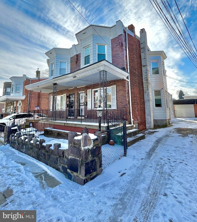 view of front of home with brick siding, a porch, and fence