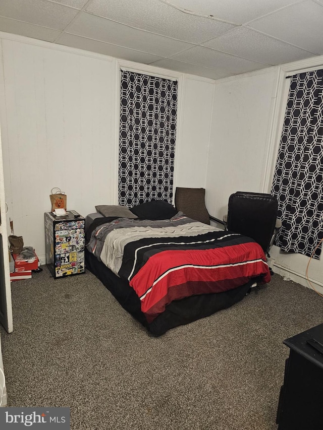 carpeted bedroom featuring a drop ceiling