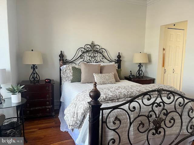 bedroom featuring crown molding and dark hardwood / wood-style floors