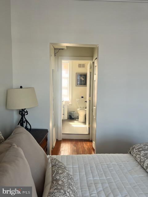 bedroom featuring ensuite bath and light hardwood / wood-style flooring