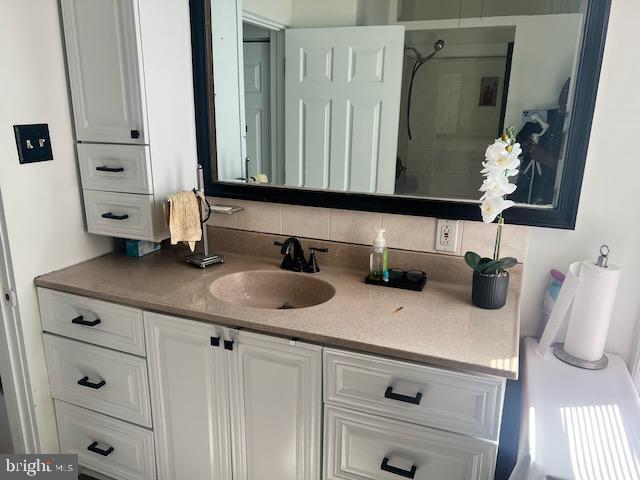 bathroom featuring walk in shower, vanity, and decorative backsplash