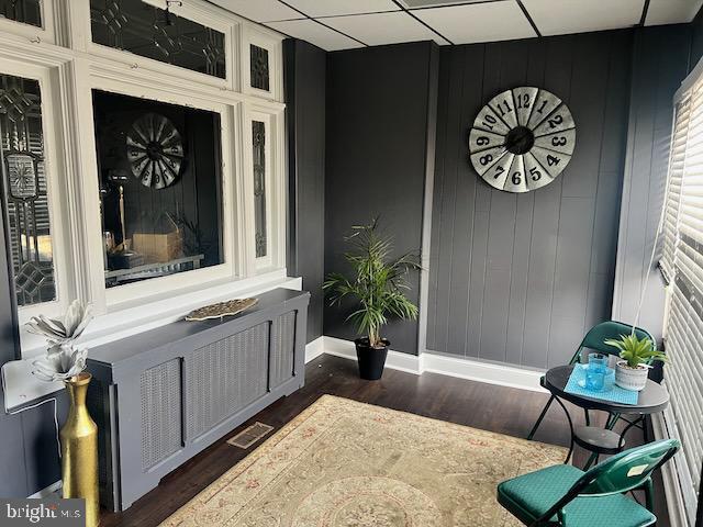 living area with dark hardwood / wood-style flooring and a paneled ceiling