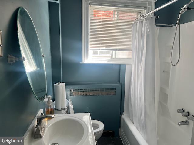 full bathroom with toilet, radiator, sink, and shower / bath combo with shower curtain