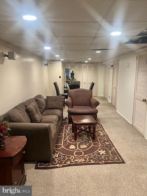 carpeted living room featuring a paneled ceiling