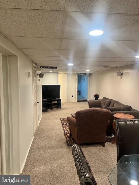 carpeted living room featuring a drop ceiling