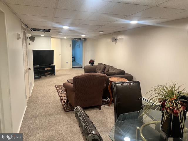 carpeted living room with a drop ceiling