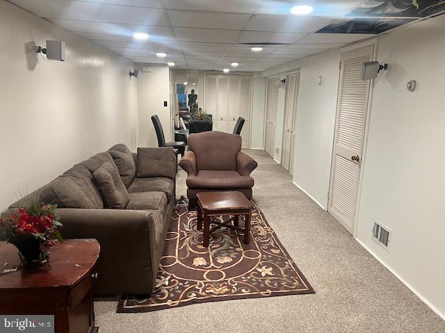 carpeted living room featuring a drop ceiling