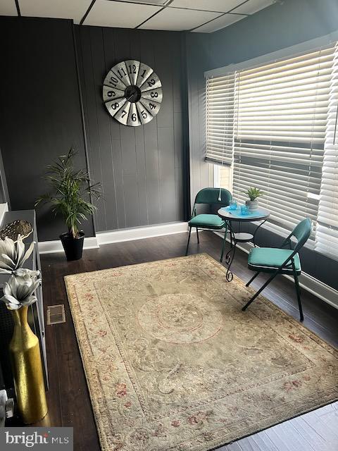 sitting room featuring dark hardwood / wood-style floors and a drop ceiling