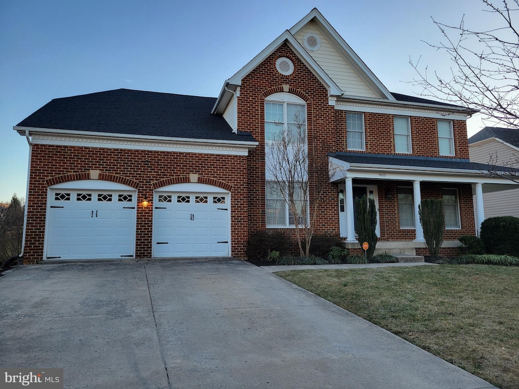 view of front of home with concrete driveway, brick siding, an attached garage, and a front yard