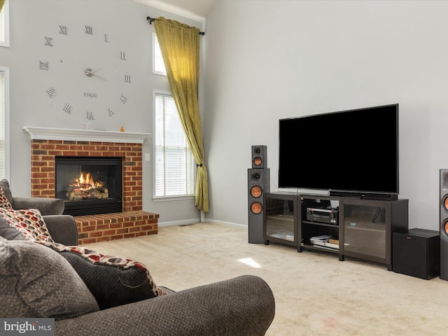 living area with baseboards, carpet, a towering ceiling, and a fireplace