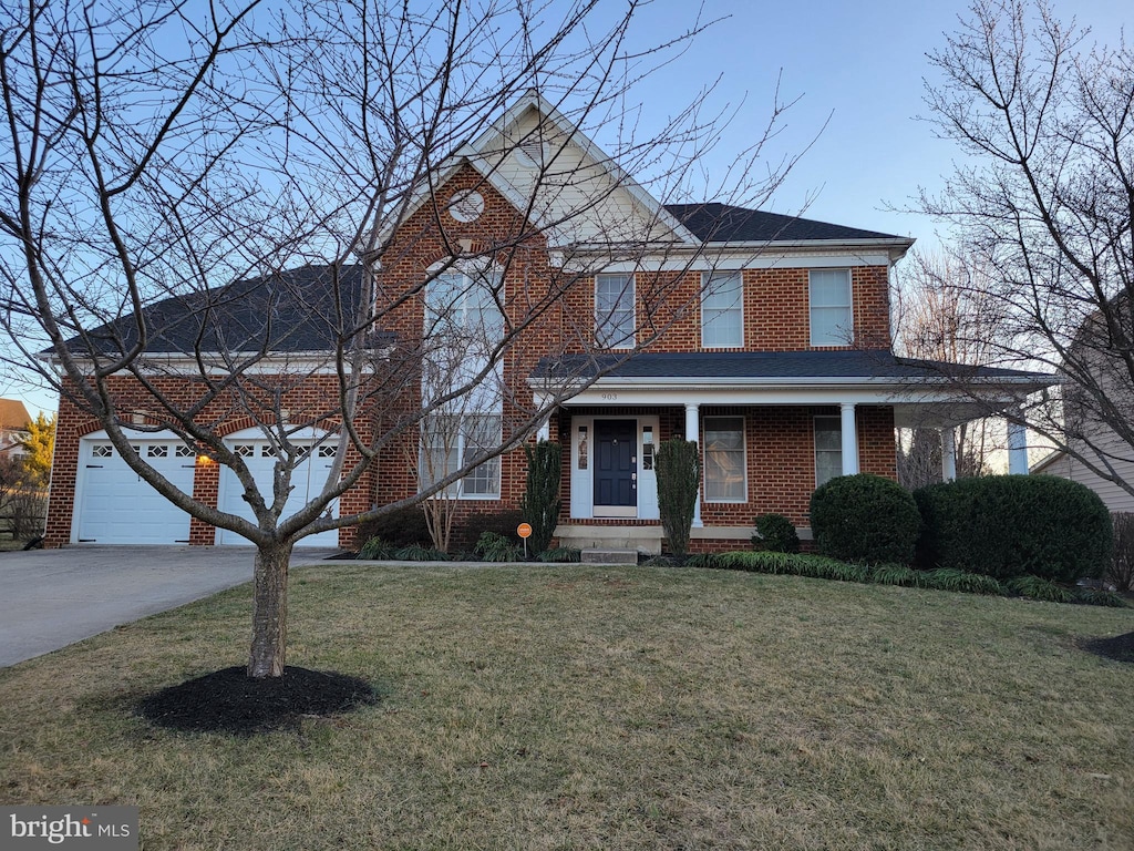 view of front of house featuring a garage, a front lawn, concrete driveway, and brick siding