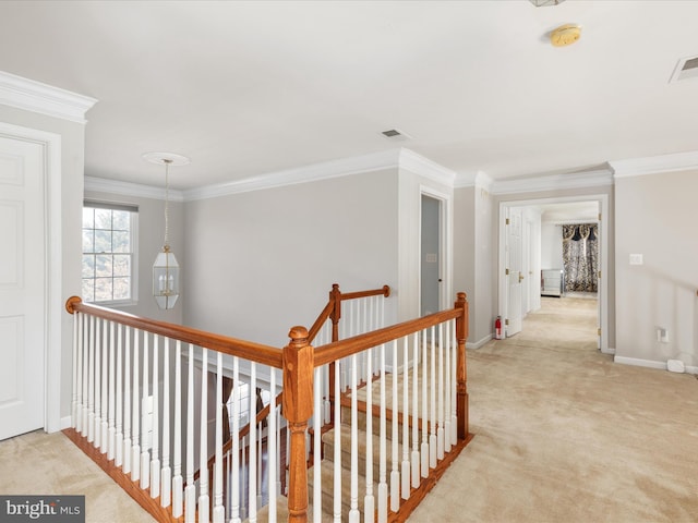 hall featuring visible vents, an upstairs landing, ornamental molding, carpet floors, and baseboards