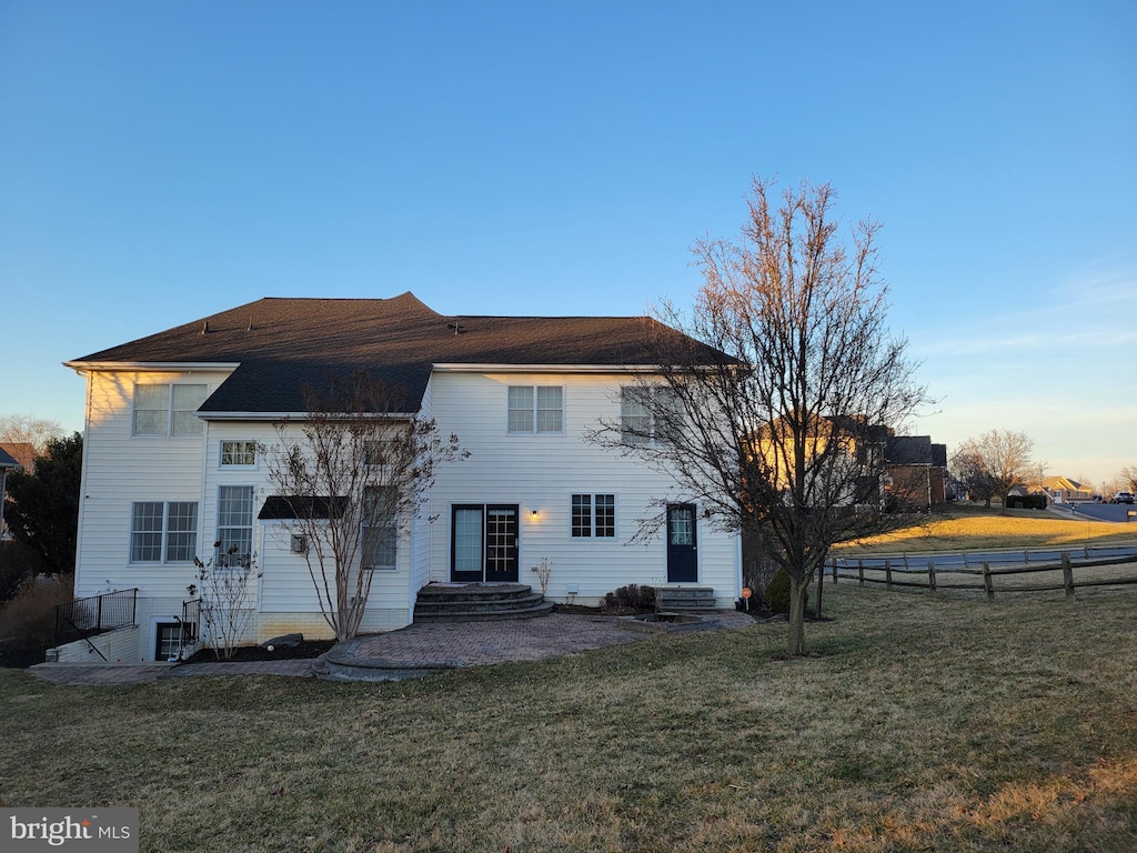 rear view of property featuring entry steps, fence, and a yard