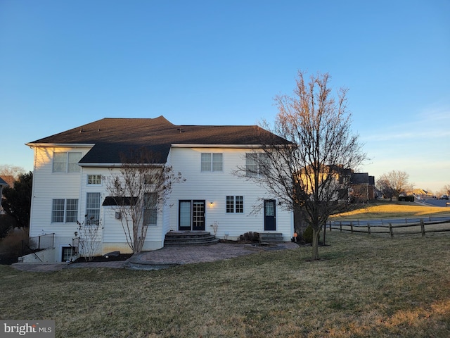 rear view of property with fence, a lawn, and entry steps